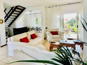 a living room with white furniture and red pillows at Secure villa in a quiet garden with pool in Albion