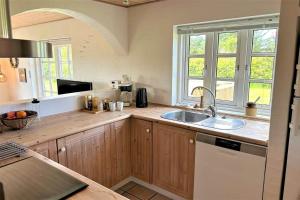 a kitchen with wooden cabinets and a sink and windows at 20708-Ulfborg-Sortebaervej-6 in Ulfborg