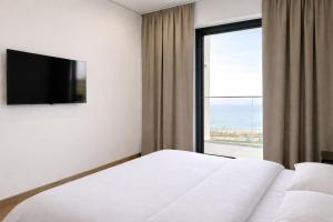 a hotel room with a bed and a large window at Next White Aparthotel OFFICIAL in Batumi +13 photos
