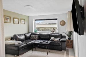 a black leather couch in a living room with a window at 70181-Ulfborg-Enghavevej-2 in Ulfborg