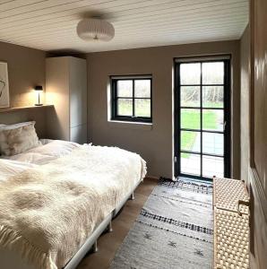 a bedroom with a large bed and two windows at 10735-Ulfborg-Graevlingevej-11 in Ulfborg