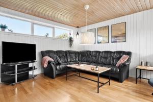 a living room with a black leather couch and a tv at 30789-Ulfborg-Akelejevej-276 in Ulfborg