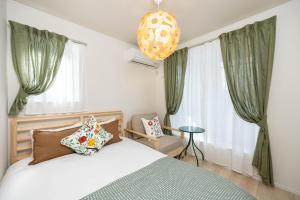 a bedroom with a bed with green curtains and a chandelier at Villa Gotemba Holidays in Gotemba