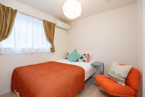 a bedroom with a bed and an orange chair at Villa Gotemba Holidays in Gotemba