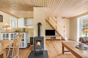 a wood stove in a living room with a table and a fireplace at 10718-Ulfborg-Baekbyvej-117 in Ulfborg