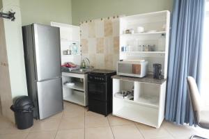 a kitchen with a black refrigerator and white cabinets at Rothman's Sea View in Pacaltsdorp