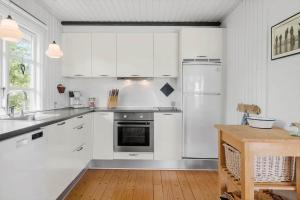 a kitchen with white cabinets and a refrigerator at 80262-Vemb-Hyttevej-103 in Vemb +17 photos