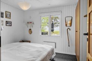 a white bedroom with a bed and a window at 80262-Vemb-Hyttevej-103 in Vemb