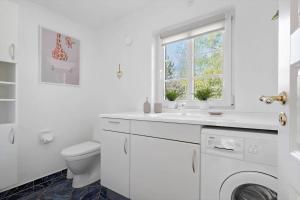 a white bathroom with a toilet and a sink and a window at 10833-Ulfborg-Graemvej-19 in Ulfborg +22 photos