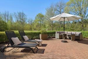 two chairs and an umbrella on a brick patio at 10833-Ulfborg-Graemvej-19 in Ulfborg
