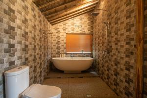 a bathroom with a tub and a sink and a toilet at The Fire Flies Garden Villa in Penginyahan