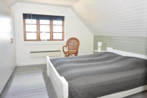 a bedroom with a bed and a chair and a window at 20038-Ulfborg-Knakvej-8 in Ulfborg