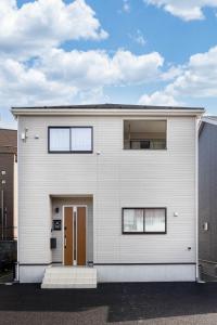 a white house with a brown door at Villa Gotemba Holidays in Gotemba
