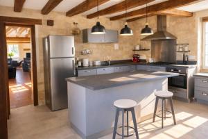 a kitchen with a large island with two bar stools at La longère du golf in Verneuil-sur-Indre