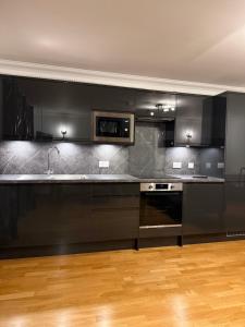 a kitchen with black cabinets and a microwave at Ardbrae Apartments in Daviot