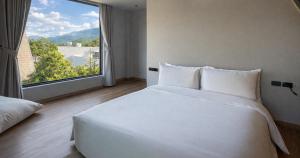 a white bed in a room with a large window at Khunkhao Paradise Khao Yai in Ban Rai Khlong Sai