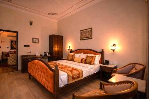 a bedroom with a large bed and two chairs at Harnawa Haveli - A Boutique Heritage Stay in Jaipur in Jaipur