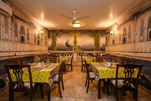 a restaurant with tables and chairs and a painting on the wall at Harnawa Haveli - A Boutique Heritage Stay in Jaipur in Jaipur