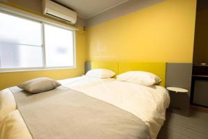 two beds in a room with yellow walls at B cycle Double Room in Biei