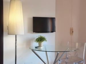 a glass table with a lamp and a television on a wall at Cameracaffè sul Lago in Arezzo