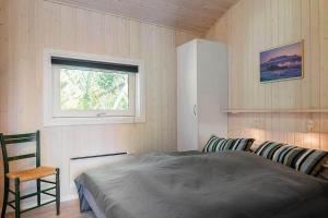 a bedroom with a bed and a window and a chair at 30816-Ulfborg-Oster-Skovvej-67 in Ulfborg