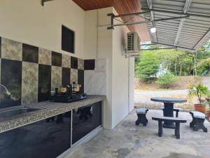 an outdoor kitchen with a counter and a table at Mutodon Green in Kuala Penyu