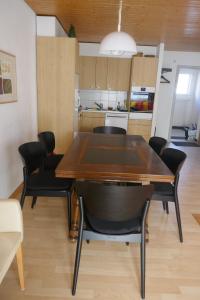 a dining room table with black chairs and a kitchen at Haus Silberblick Anrig in Grächen
