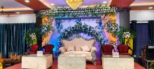 a room with a stage with a couch and chairs at Hotel Kunj Palace in Habibnagar