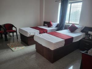 a bedroom with two beds and a chair at Hotel Kunj Palace in Habibnagar