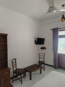 a living room with two chairs and a bench and a tv at Robert Ayurveda Villa in Bentota