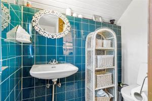 a blue tiled bathroom with a sink and a mirror at 30327-Ulfborg-Grastensborgvej-38 in Ulfborg