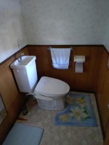 a bathroom with a toilet with a sink and a flower rug at ペンション自給自足 in Miyazu