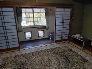 an empty room with two windows and a rug at ペンション自給自足 in Miyazu