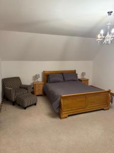 a bedroom with a bed and a chair and a chandelier at Ardbrae Apartments in Daviot