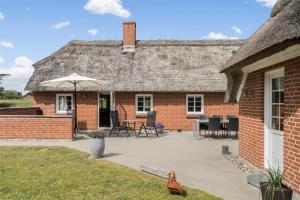 a brick house with an umbrella and a patio at 20733-Ulfborg-Sortebaervej-4 in Ulfborg