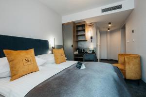 a bedroom with a large bed with white sheets and yellow pillows at Hotel M4 Boutique in Krakow