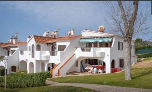 a large white house with birds on the roof at Apartment for 6 with a private terrace in Son Bou in Son Bou