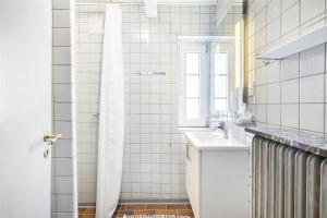a white tiled bathroom with a sink and a window at 20033-Ulfborg-Vesterhavsvej-15 in Ulfborg +20 photos
