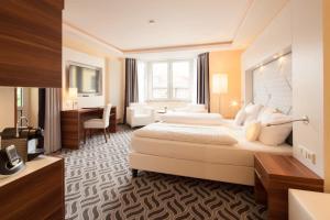 a hotel room with two beds and a desk at Moin Hotel Cuxhaven in Cuxhaven +42 photos