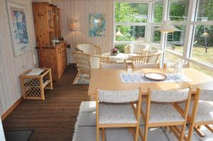 a dining room with a table and chairs and windows at 30061-Ulfborg-Kaprifolievej-6 in Ulfborg