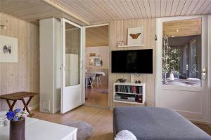 a living room with a television and a room with a table at 30394-Ulfborg-Kaprifolievej-8 in Ulfborg