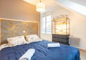 a bedroom with a blue bed and a large window at L'Eclose in Le Guilvinec