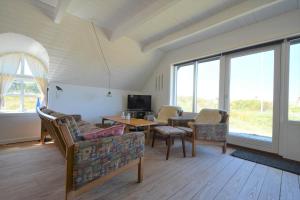 a living room with chairs and a table and windows at 20261-Ulfborg-Vederso-Klitvej-20 in Ulfborg +10 photos