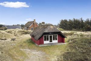 a small house with a grass roof on a field at 20261-Ulfborg-Vederso-Klitvej-20 in Ulfborg