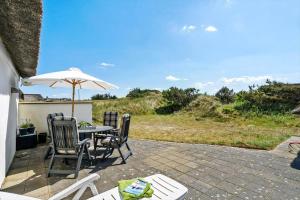 a patio with a table and chairs and an umbrella at 20157-Ulfborg-Revlingvej-8 in Ulfborg