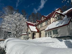 a house covered in snow with a pile of snow at ray of hakuba 白馬の輝き in Hakuba