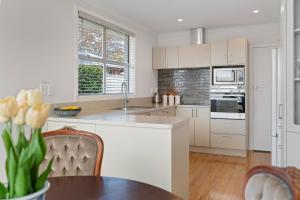 a kitchen with white cabinets and a table at Roslyn Sanctuary Highgate Dunedin in Dunedin