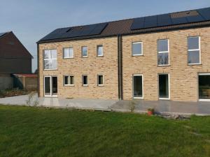 a brick building with solar panels on the roof at Au pays des cigognes in Cambron-Casteau