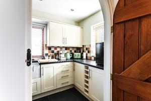 a kitchen with white cabinets and black counter tops at New House Barn in Ashbourne