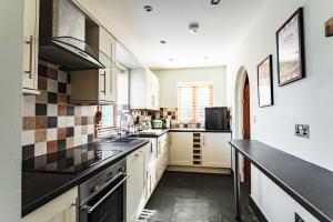 a kitchen with white cabinets and black counter tops at New House Barn in Ashbourne